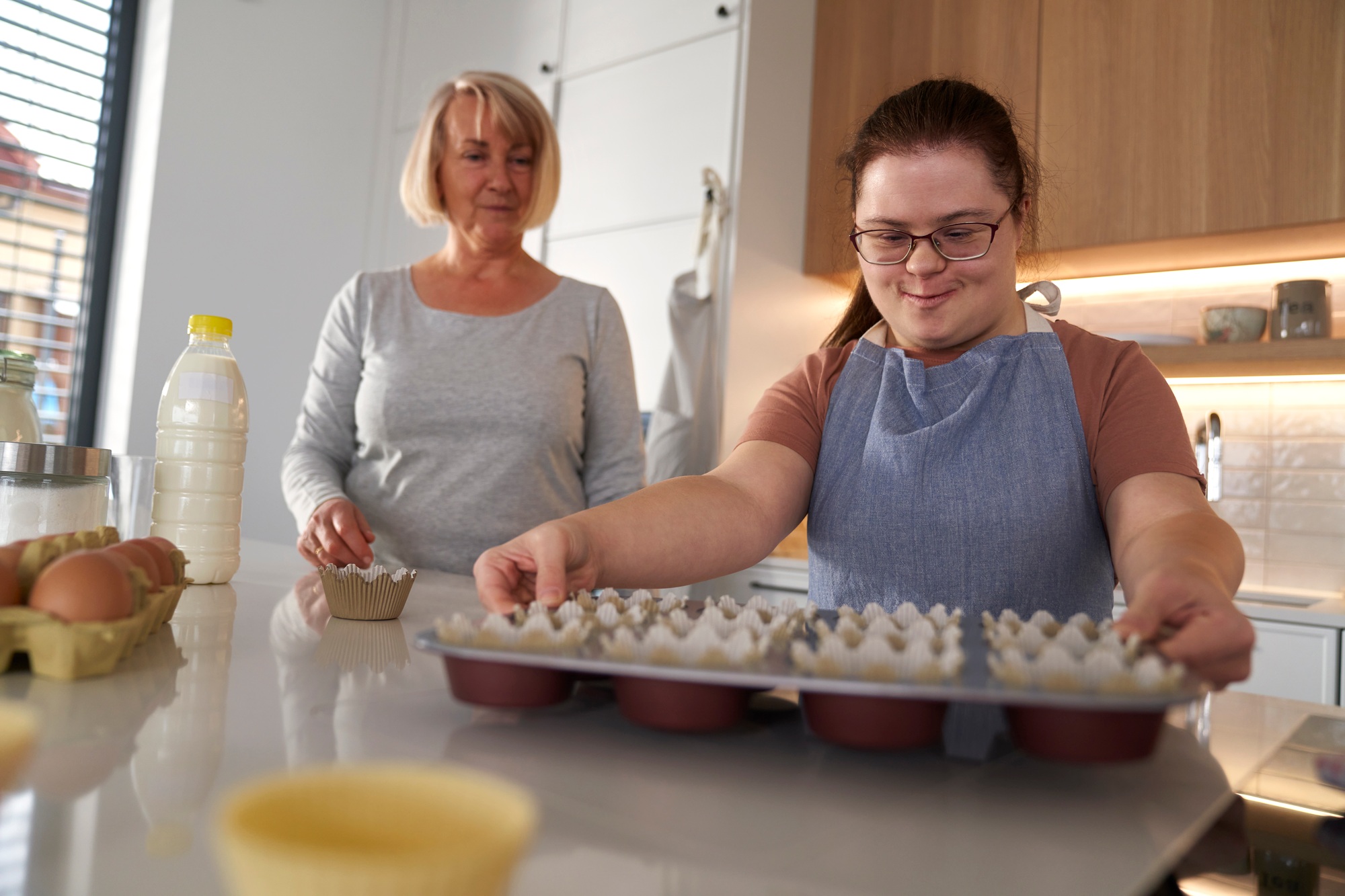Down syndrome woman holding tray with homemade cupcakes