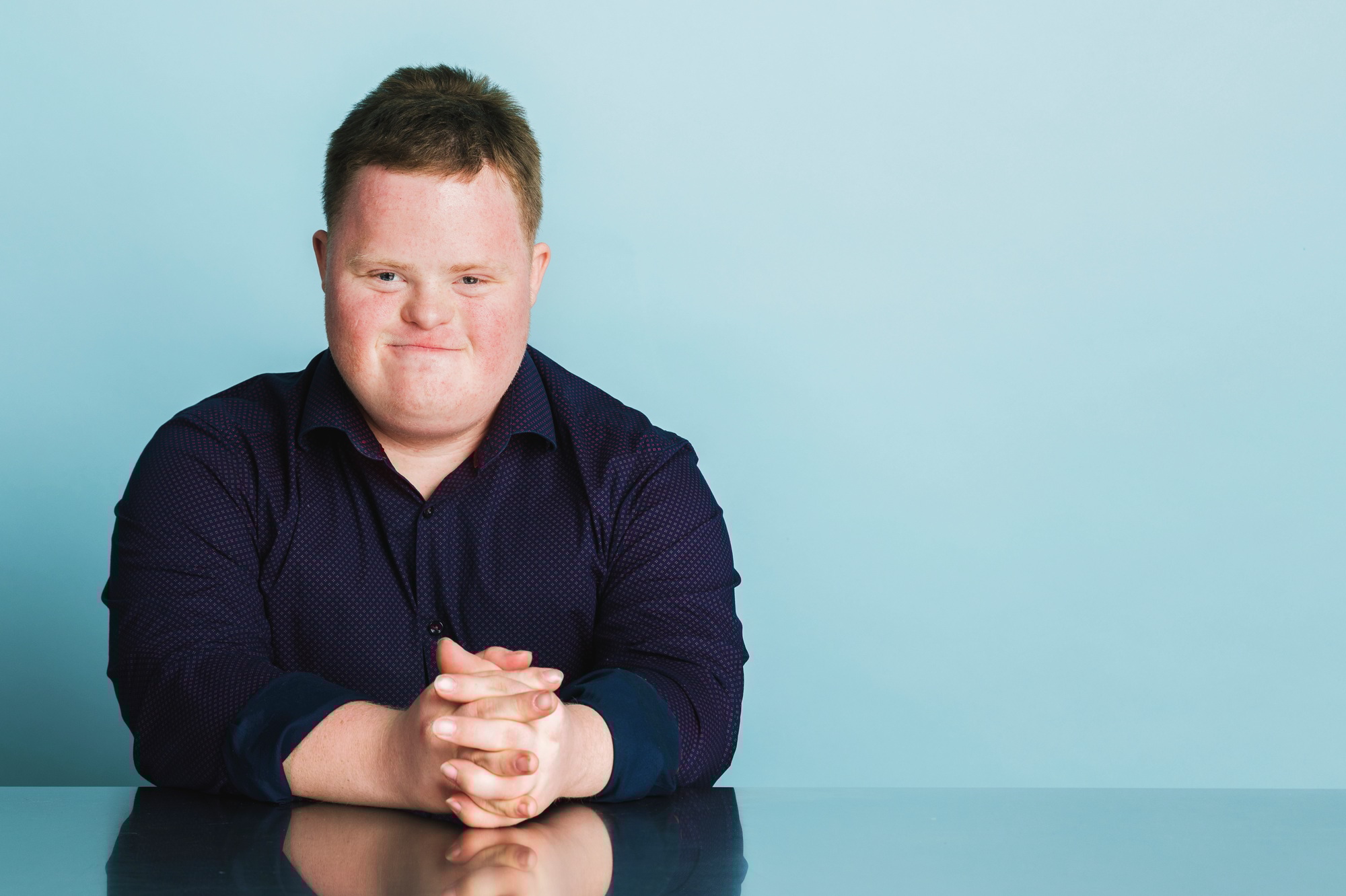 Confident boy with down syndrome sitting on a chair